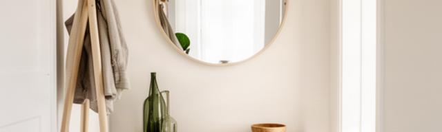 Lichte hal met ronde spiegel, houten kapstok en decoratieve mand